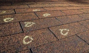 Chalk circles marking damage spots on roof shingles