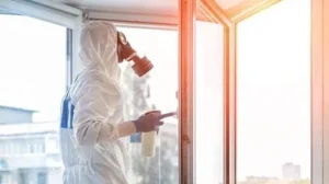 Technician cleaning soot from a window frame in hazmat suit